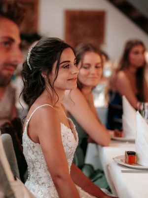 Braut, Bräutigam und Gäste sitzen am Tisch